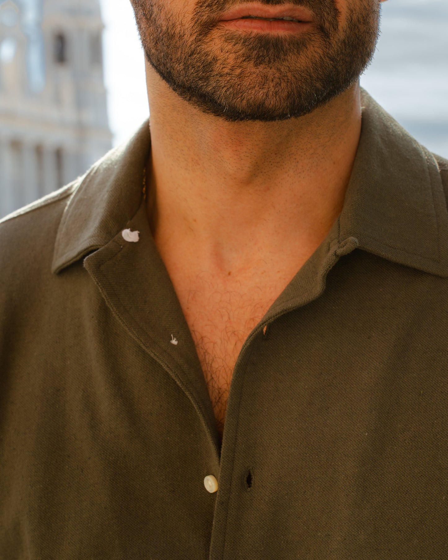 Close up of model outside wearing the custom oxford polo shirt for men by Luxire in olive green 3