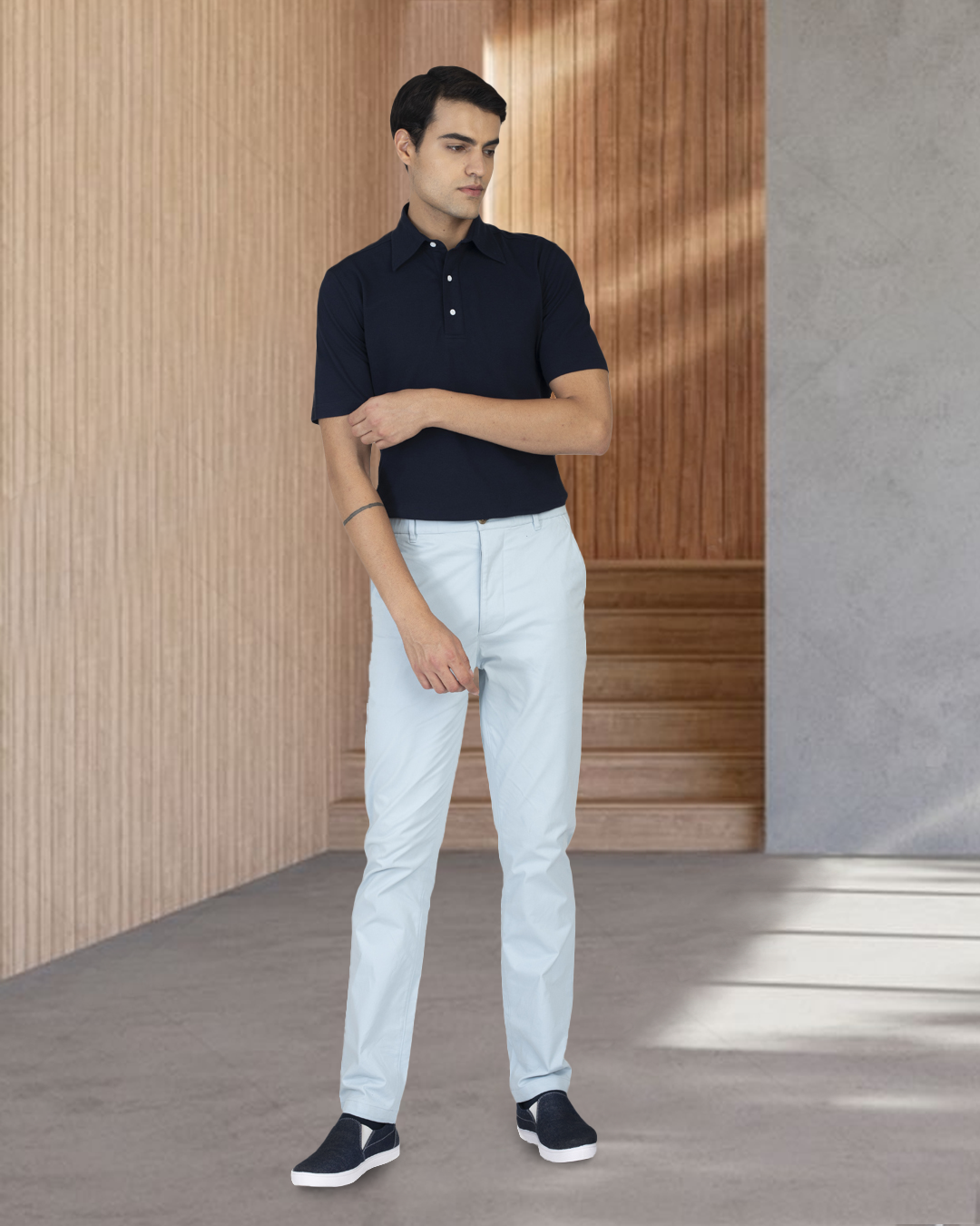 Model wearing the custom oxford polo shirt for men by Luxire in navy with white pants 4