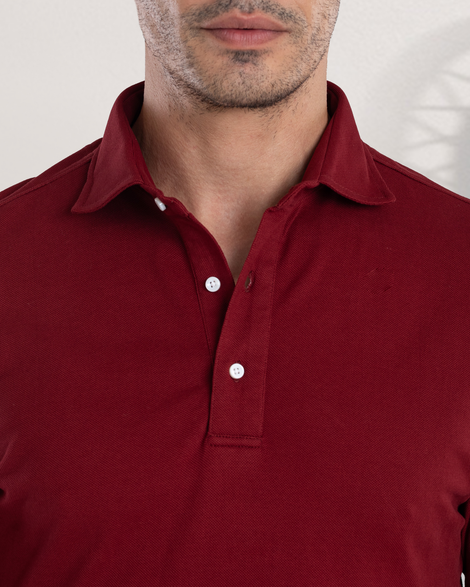 Close up of model wearing the custom oxford polo shirt for men by Luxire in maroon