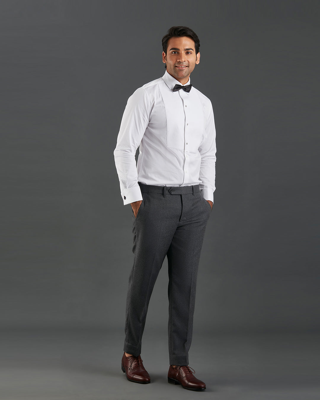 Model wearing mens tuxedo shirt by Luxire in white with black bow tie hands in pockets