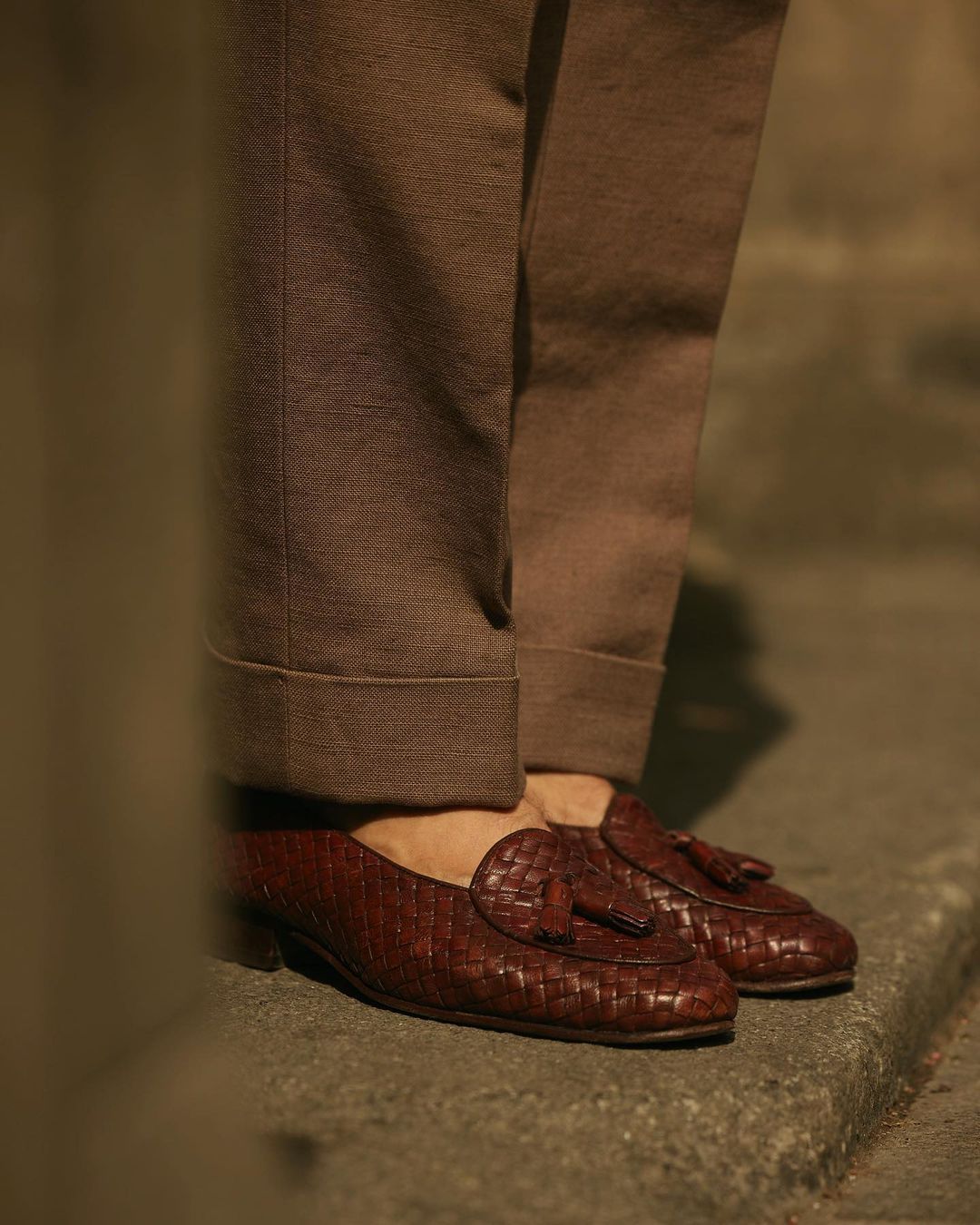 Model in shoes wearing custom linen canvas pleated pants for men by Luxire in brown