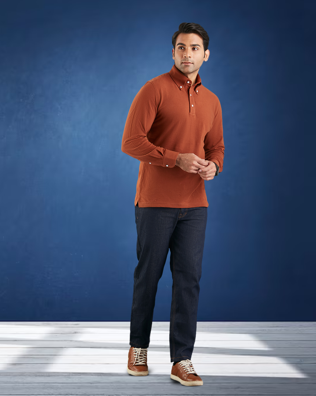 Front of model wearing the custom oxford polo shirt for men by Luxire in copper hands together