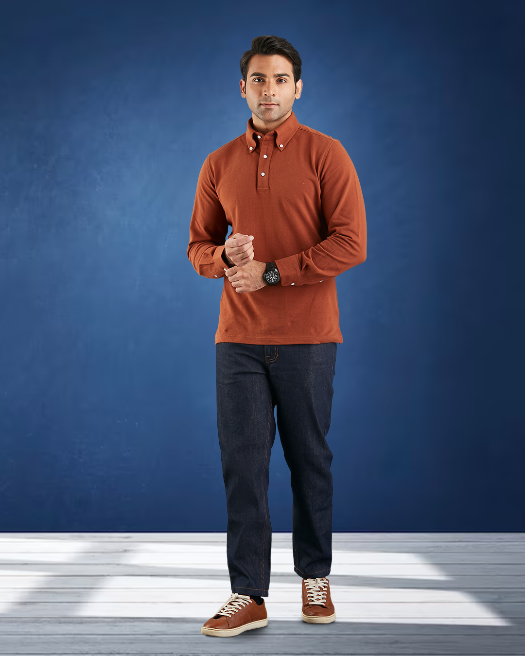 Model wearing the custom oxford polo shirt for men by Luxire in copper hands together with blue background