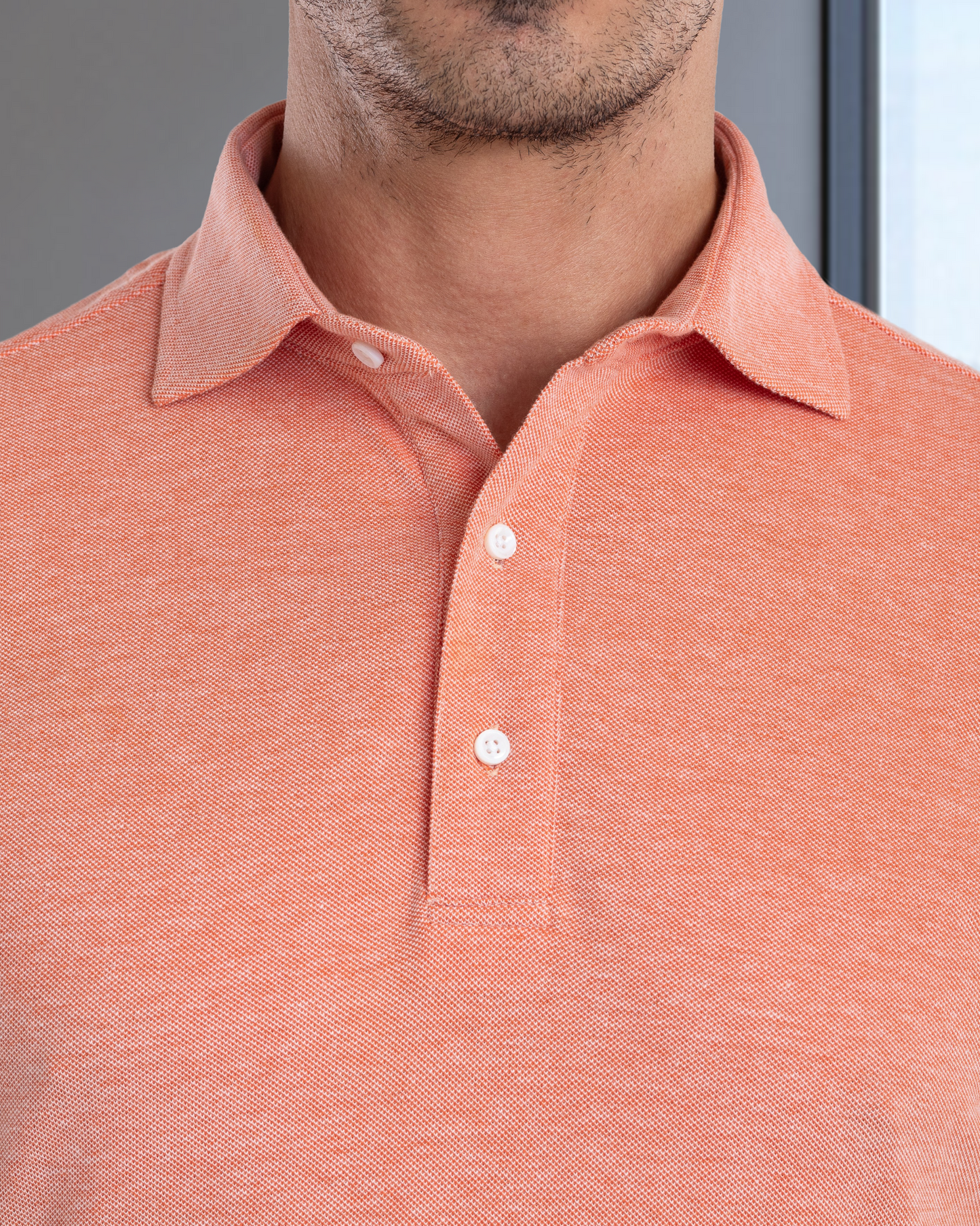 Close up of model wearing the custom oxford polo shirt for men by Luxire in orange white